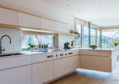 Küche in Weißtanne und weißen Fronten mit Bora Geräten, modern und mit Sichtbeton