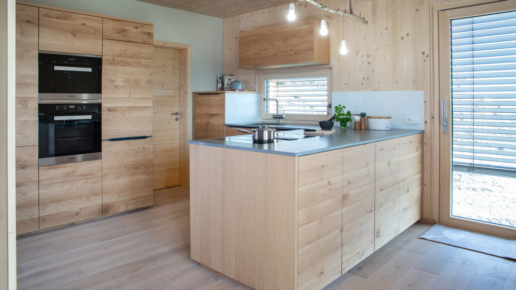 Massivholz Küche aus Eiche mit Naturstein Arbeitsplatte Atlantis von Strasser in einem Thoma Holz100-Haus bei Ansbach